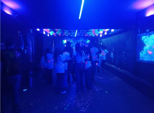 Adolescentes conviviendo bajo la luz negra del salón