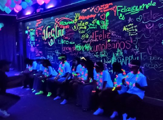 Muro de graffiti fluorescente firmado por los invitados de la fiesta