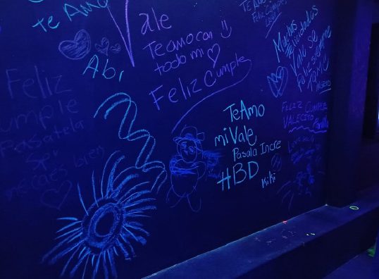 Muro con mensajes de cumpleaños escritos por los invitados en tiza fluorescente