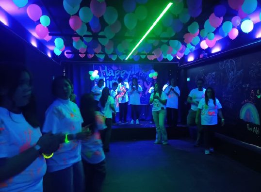 Adolescentes bailando con barras luminosas en una fiesta neón en WeGlow