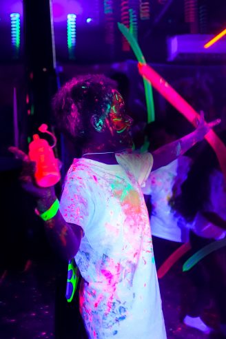 Niña jugando con barras luminosas en una fiesta glow in the dark