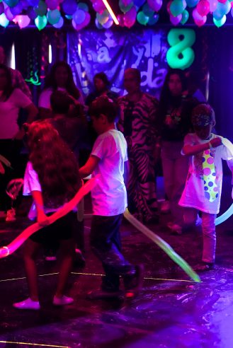 Niños bailando con barras de espuma luminosas en la pista