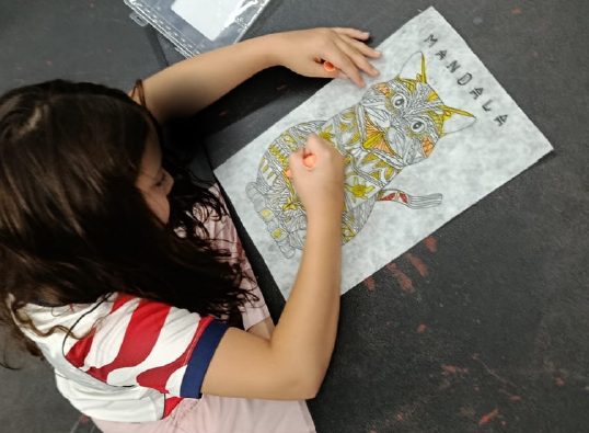 Niña dibujando en la mesa de actividades de la ludoteca