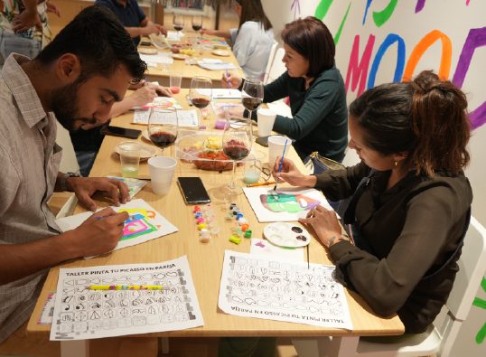 Taller de pintura en curso alrededor de la mesa larga del salón WeGlow en Roma Norte