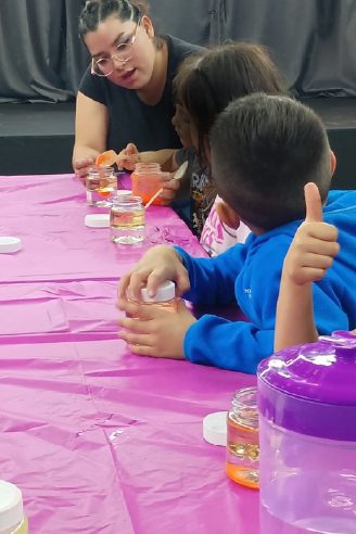 Facilitadora acompañando a niños en una actividad de mesa durante el Viernes de Consejo en WeGlow