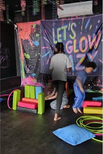 Niños jugando frente al telón Let's Glow en el salón de WeGlow