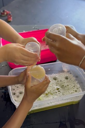 Niños haciendo un experimento de slime con vasos y materiales