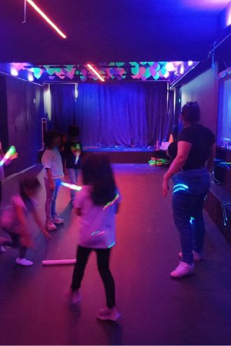 Niños bailando con luz negra en el salón neón de WeGlow